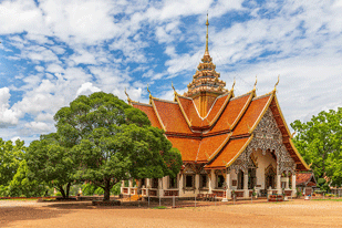 Ornate Thai temple framed by trees under a bright sky
